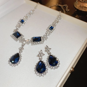 Detail of silver jewelry set with blue rectangular gemstones and crystal accents
