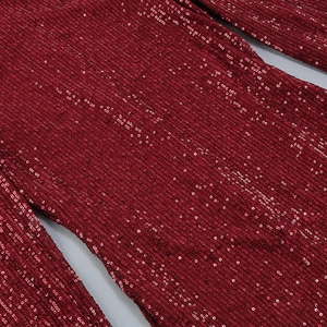 Gros plan des paillettes bordeaux sur le tissu de la robe à manches longues