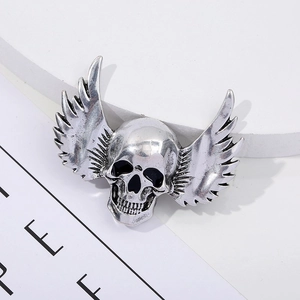 Detailed view of a vintage silver winged skull brooch with gothic punk style carvings
