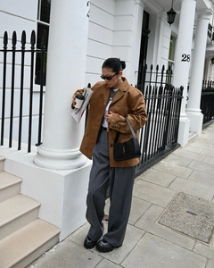 Detail shot of a women caramel brown suede blazer paired with dark grey wide-leg trousers