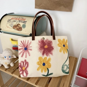 Detail of floral canvas tote bag featuring brown leather handles and a metal snap closure
