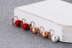 Vue détaillée de boucles d'oreilles perles en rouge, champagne et blanc en or rose
