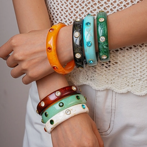 Colorful acrylic geometric bangles with rhinestones worn by a model in layers