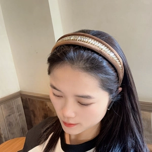Serre-tête en velours marron avec strass dorés porté par un mannequin pour l'effet de hauteur