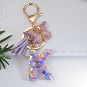 Purple glitter resin letter K keychain with butterfly charm and soft tassel on gold clasp