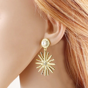 Boucles d'oreilles pendantes dorées avec perle blanche et strass portées par mannequin