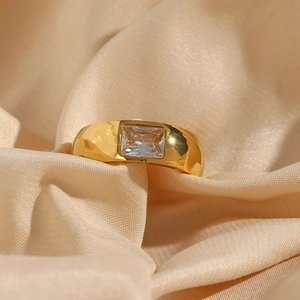Close-up of 18K gold plated ring with square zircon on champagne silk background