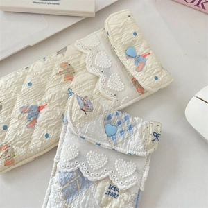 Detailed shot of quilted fabric pouches with bear patterns and blue heart buttons