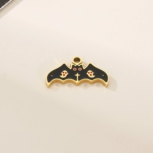 Detailed view of a gold-tone bat pendant with black enamel inlay and red accents