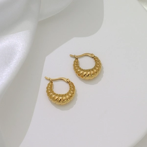 Macro view of golden croissant hoop earrings featuring elegant twisted texture and glossy finish