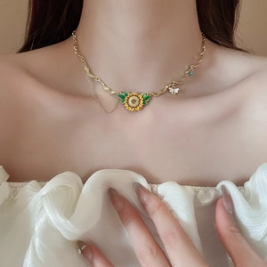 Detail of sunflower and bee necklace with gold chain and drip oil craft on model