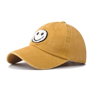 Detail of vintage washed yellow cotton baseball cap with embroidered smiley face patch