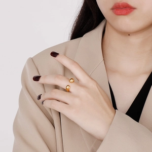 Close-up of golden open droplet ring with a high-polished finish on model's hand
