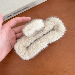 Détail d'une pince à cheveux en fourrure beige sur un bureau avec un guide textile
