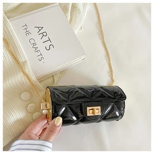 Detail of black quilted cylindrical chain bag with gold hardware and pearl side accent