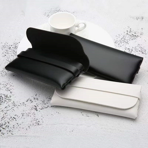 Minimalist black and white faux leather eyewear pouches on a grey marble table