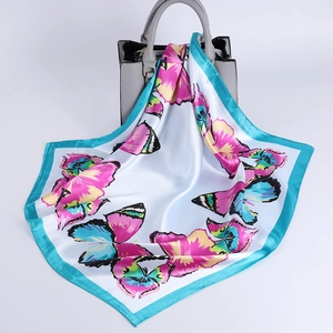 Silk satin square scarf with colorful butterfly print and blue border on a handbag
