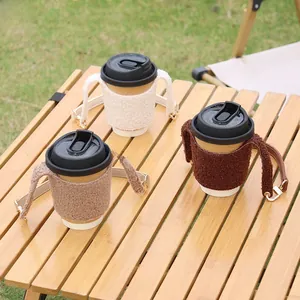 Three lamb wool coffee cup sleeves with leather handles on a wooden table outdoors