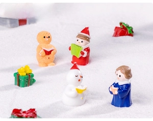 Macro shot of resin Christmas choir figurines with snowman and gingerbread man on snow