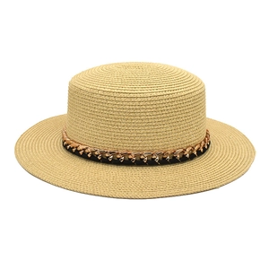Détail du chapeau de paille à sommet plat avec sangle en cuir noir et chaîne dorée