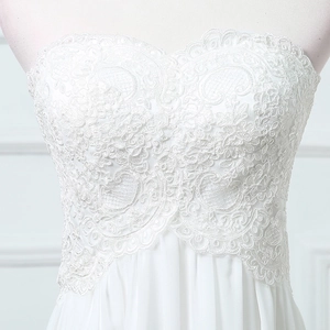 Close-up detail of white lace floral embroidery and mesh texture on strapless bridal gown