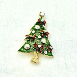Close-up of a green Christmas tree brooch with golden edges and sparkling rhinestones