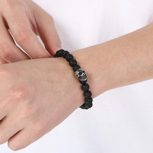 Detail of beaded lava stone bracelet featuring a silver skull charm on wrist