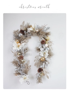 Detail of Christmas wreath featuring white flowers, pine cones and champagne gold ornaments