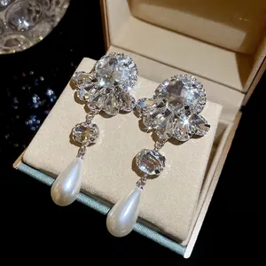 Elegant silver earrings with sparkling crystals and teardrop pearls in a jewelry box