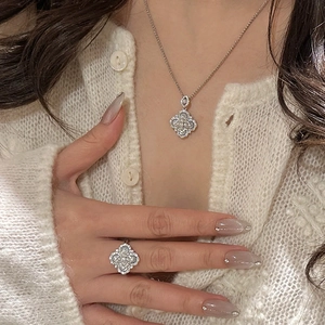 Close-up of elegant silver clover necklace and ring set with white mother of pearl and zircons