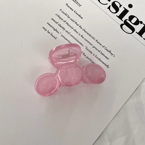 Detail of pink acrylic hair claw clip with spring mechanism on white paper background