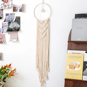 Detailed macro view of woven beige cotton macrame dreamcatcher with pink crystal center stone