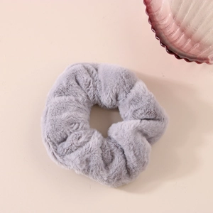 Dettaglio dell'elastico per capelli in peluche grigio ad alta elasticità su base beige