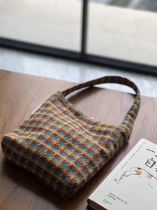 Detail of vintage knit shoulder bag with yellow and blue plaid texture on a wooden table
