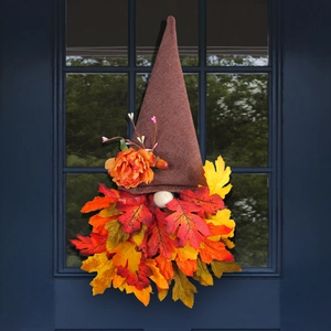 Autumn gnome wreath with pointed hat and fall leaves hanging on a dark blue door