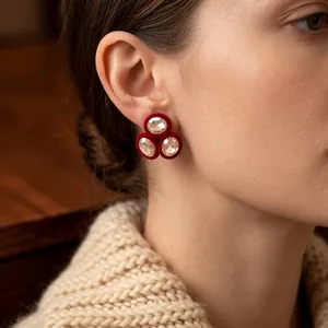 Red velvet oval earrings with triple crystal stones worn by model in warm autumn setting