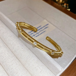 Macro view of gold-plated brushed open bangle featuring three brilliant round zircons