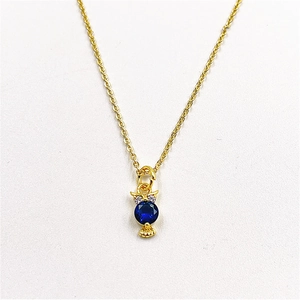 Macro shot of owl pendant with blue crystal and cubic zirconia inlay on gold chain
