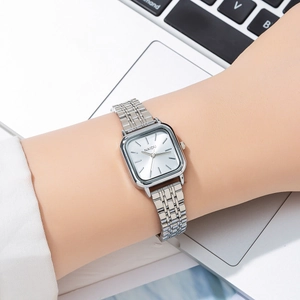 Close-up of minimalist square silver steel watch worn on wrist over a laptop background