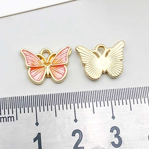 Detail of pink enamel butterfly charm showing 15mm size measurement and golden metal back