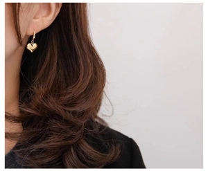 Close-up of elegant gold heart dangle earring worn on model for a vintage look