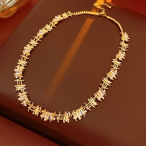 Gros plan du collier en or avec maillons carrés en zircone sur surface en cuir brun