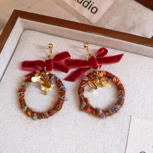 Close-up of handmade Christmas wreath earrings with red velvet bow and gold bells