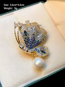 Macro shot of luxury gold butterfly brooch with blue stones, pearls and size dimensions