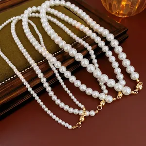 Vintage pearl necklaces with magnetic gold clasps in four sizes on a dark green velvet tray