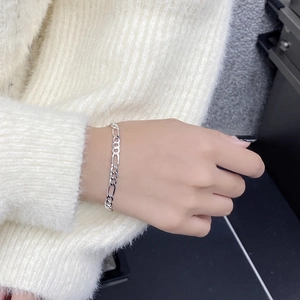 Classic silver Figaro chain bracelet worn by a model in a cozy white knit sweater