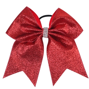 Detail of a red glitter hair bow with sparkling rhinestone centerpiece on black elastic