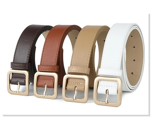 Detailed view of four leather belts in dark brown, brown, khaki, and white with metal buckles