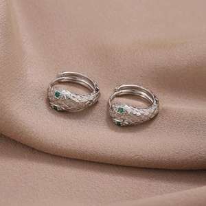 Unisex silver snake hoop earrings with green zircon eyes on champagne silk fabric