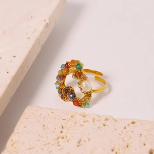 Golden open ring with colorful beads and white pearl heart on travertine stone
